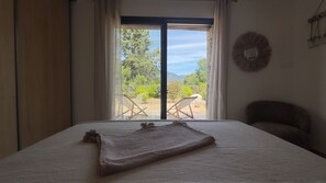 A bedroom with a bed, a view of the outdoors, and a chair. - Charming sheepfold, comfortable and ideally located (Figari)