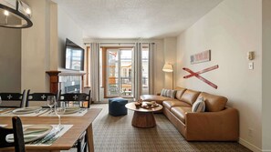 Ein modernes Wohnzimmer mit Essbereich, einem Ledersofa, einem Couchtisch und einem an der Wand befestigten Fernseher.