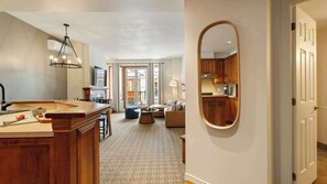 Eine moderne Küche mit einer großen Kochinsel, ein Essbereich mit Tisch und Stühlen sowie ein Wohnzimmer mit Sofa und einem großen Spiegel an der Wand.