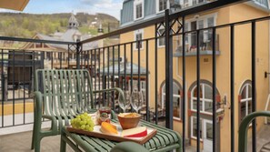 Ein Balkon mit Tisch, gedeckt für eine Mahlzeit, mit Käseplatte, Trauben und einer Schale Chips.
