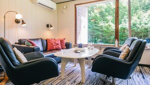 A room with a sofa, two chairs, a table, and a large window with a view of trees. - 6 Person Holiday Home in Hadsund (Hadsund)