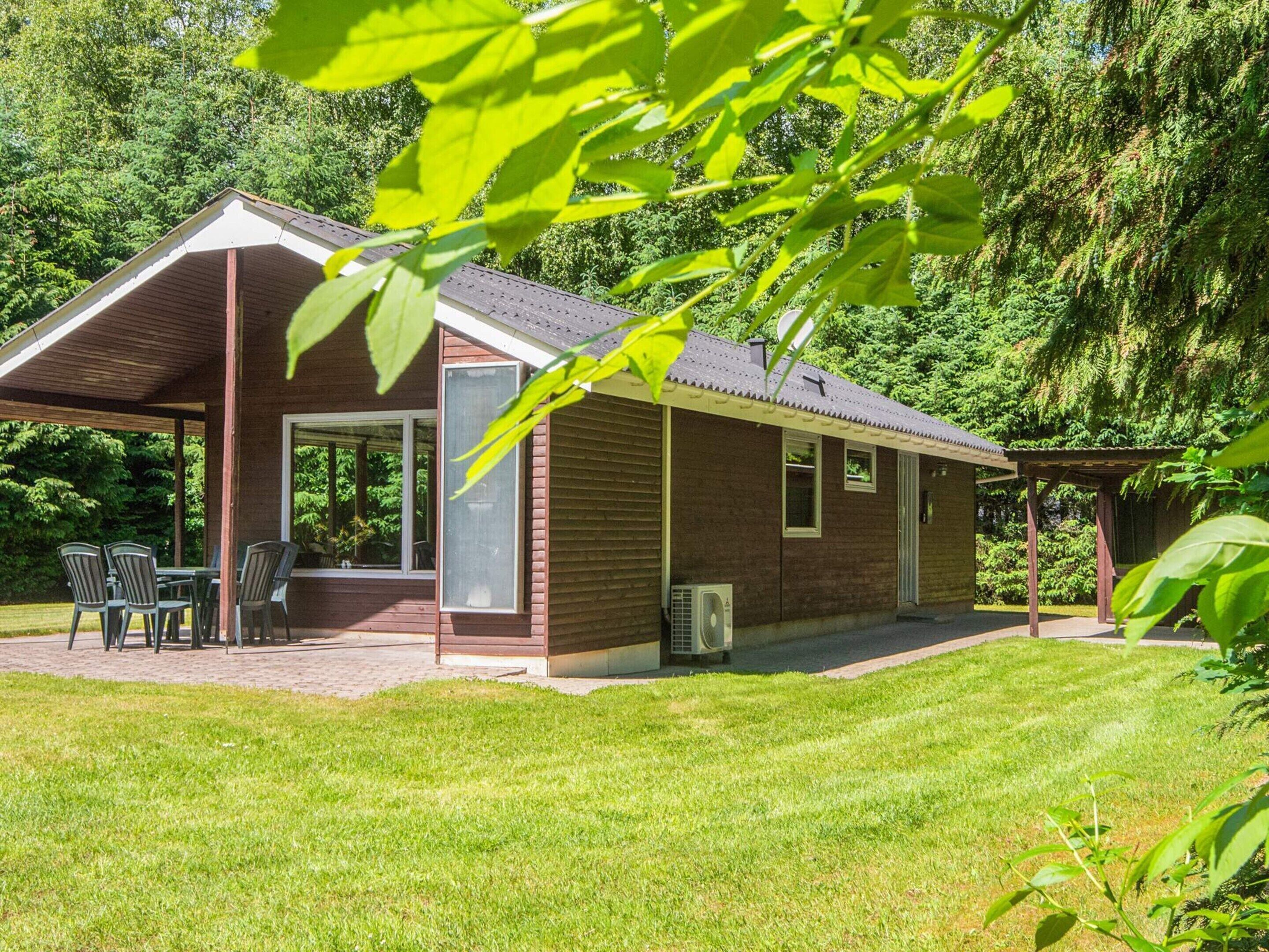 A single-story brick house with a covered patio, a small outdoor seating area, and a lawn.