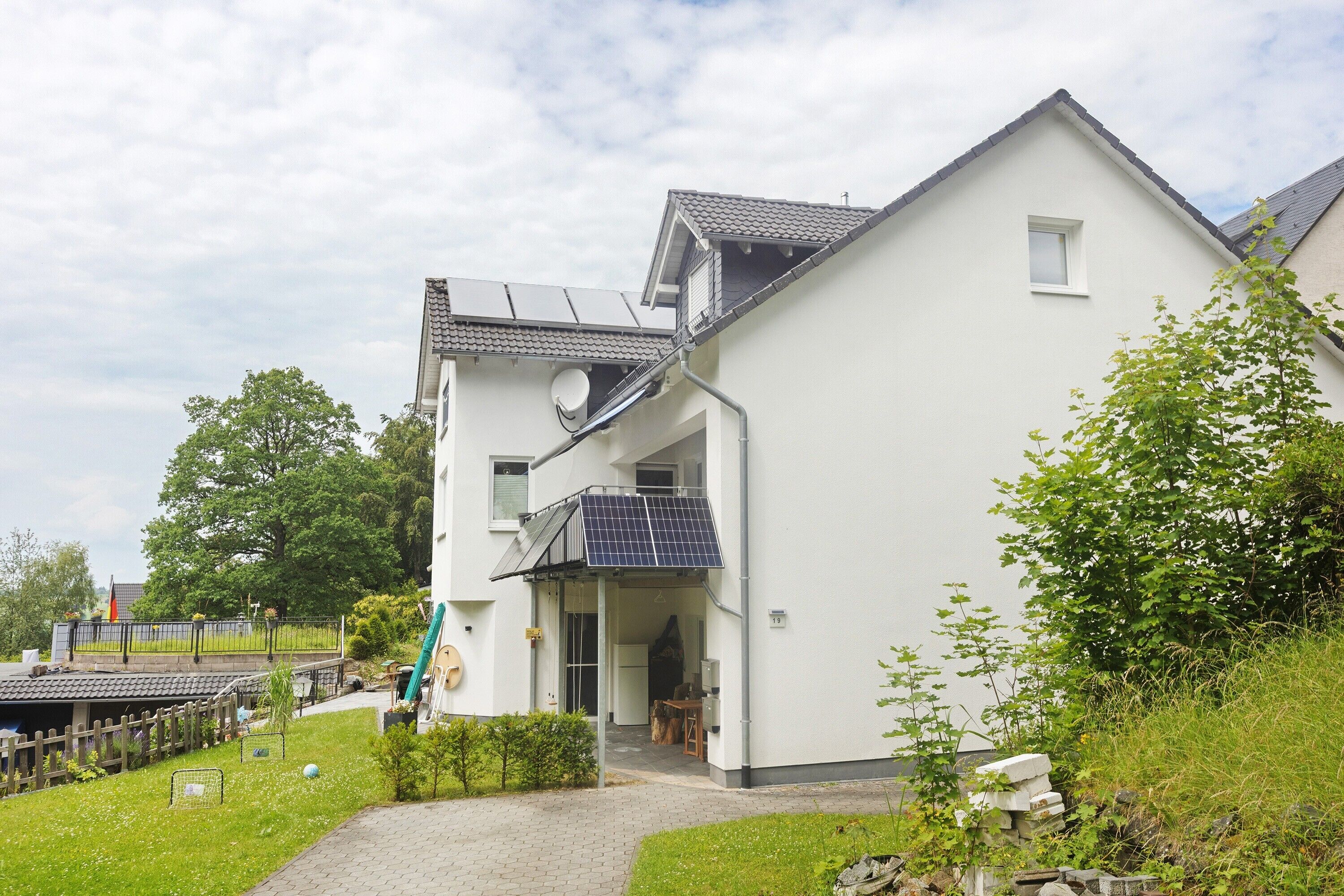 A residential building with a sloped roof, a satellite dish, and a small balcony.