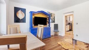 Un comedor con una mesa y sillas de madera, un armario azul y piso de madera.