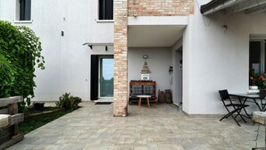 A courtyard with a brick column, a wooden bench, a table, and chairs. - Bed and Breakfast Al Vecio Morer 'Camera Rose' with Air Conditioning (San Donà di Piave)