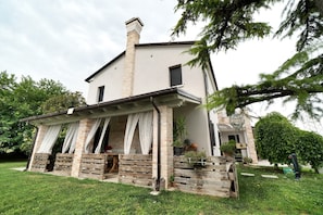 Ein zweistöckiges Haus mit einer Veranda, einem Schornstein und einem gepflegten Rasen.