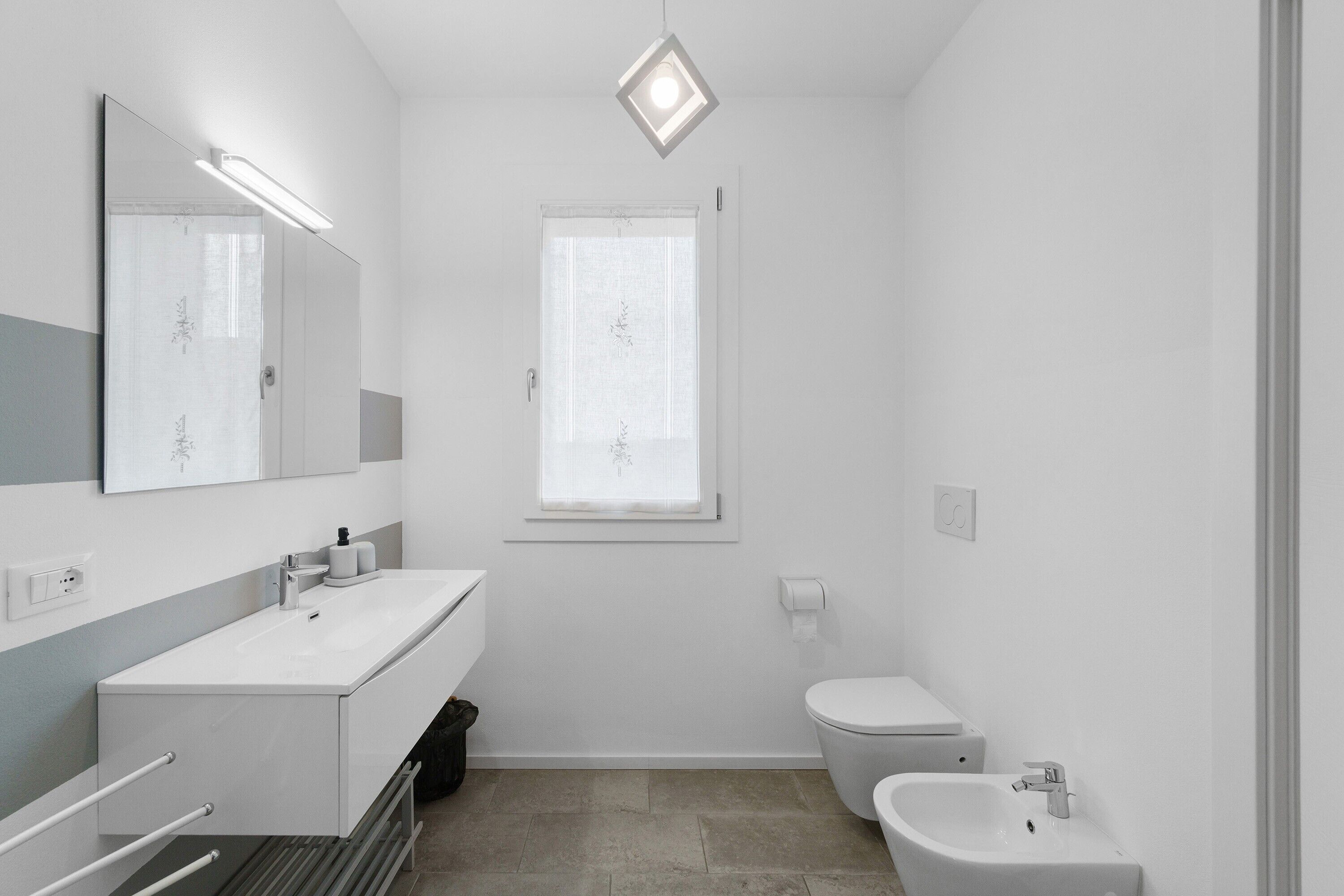 Ein modernes Badezimmer mit großem Spiegel, Waschbecken, Toilette und Bidet.