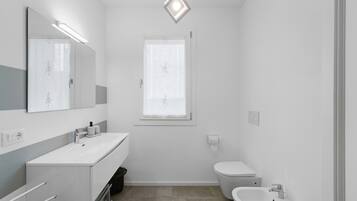 Ein modernes Badezimmer mit großem Spiegel, Waschbecken, Toilette und Bidet.