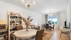 A dining area with a round table, chairs, a chandelier, a wine rack, and a window with curtains. - Bed and Breakfast Al Vecio Morer 'Camera Rose' with Air Conditioning (San Donà di Piave)