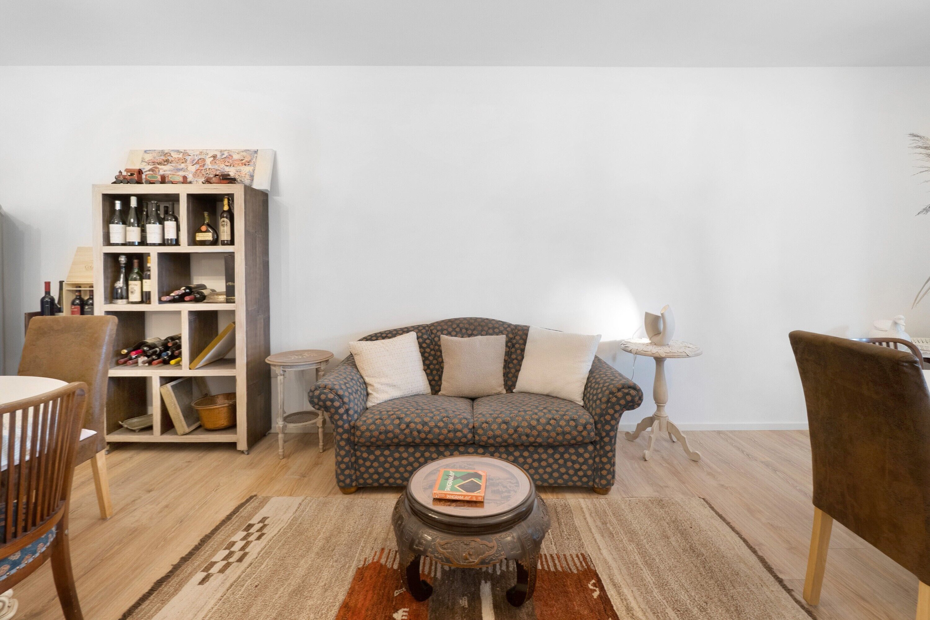 Een woonkamer met een gestreept sofa, een houten boekenkast, een ronde salontafel en een klein bijzettafeltje.