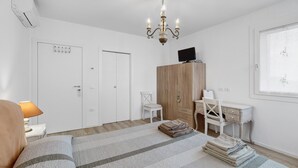 A bedroom with a bed, a desk, a chair, a wardrobe, and a chandelier. - Bed and Breakfast Al Vecio Morer 'Camera Rose' with Air Conditioning (San Donà di Piave)