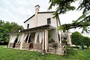 A two-story house with a covered porch, a chimney, and a well-maintained lawn. - Twin Room with Air Conditioning (San Donà di Piave)