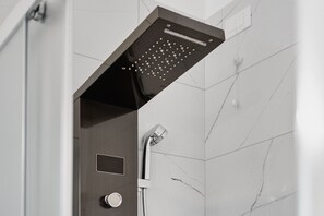 A modern showerhead with multiple nozzles, a control panel, and a wall-mounted faucet. - Twin Room with Air Conditioning (San Donà di Piave)