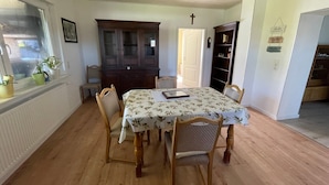 A dining area with a wooden table, four chairs, a cabinet, and a bookshelf.