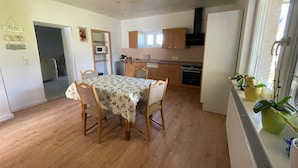 A kitchen with wooden cabinets, a dining table with chairs, a microwave, and a stove.