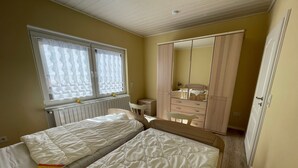 A bedroom with two beds, a wardrobe, a mirror, and a radiator.