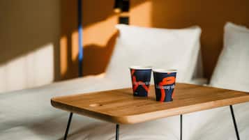A wooden table with two cups on a bed.