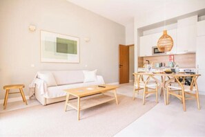 Ein modernes Wohnzimmer mit Sofa, Couchtisch und Essbereich mit Stühlen.
