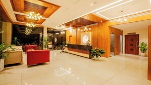 A hotel lobby with a reception desk, seating area, and a modern chandelier. -  Hotel Grand Royal Paika (POOVARANI)