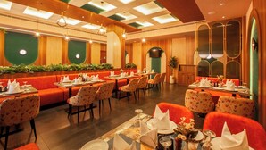 A restaurant with booths and tables, wooden ceiling, and green wall accents. -  Hotel Grand Royal Paika (POOVARANI)