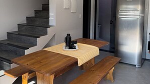 Et moderne køkken med et træbord, bænke, et rustfrit stål køleskab og en trappe.