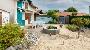 Een huis met een terras, vuurkorf en een kleine tuin.