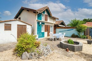 A two-story house with a tiled roof, a garden with a fire pit, and outdoor seating.