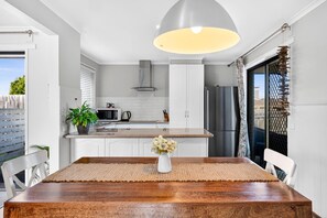 Une cuisine moderne avec des armoires blanches, un réfrigérateur en acier inoxydable, un four à micro-ondes et un luminaire suspendu.
