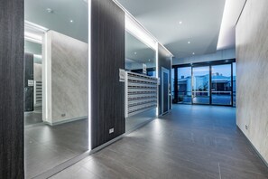 A modern hotel lobby with a glass entrance, a reception desk, and a view of the outside. - The Signature: 3BR, Crown & Stadium, Rooftop BBQ (Burswood)