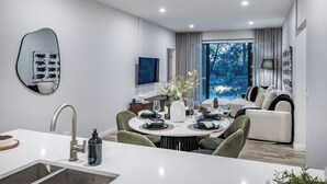 Un comedor moderno con una mesa redonda, sillas y una encimera de cocina con fregadero.