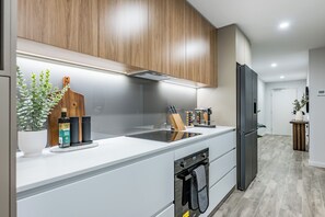 A modern kitchen with wooden cabinets, a stainless steel sink, and a built-in oven. - Luxury Burswood Stay · Crown, Stadium & Swan River · Sleeps 6 (Burswood)