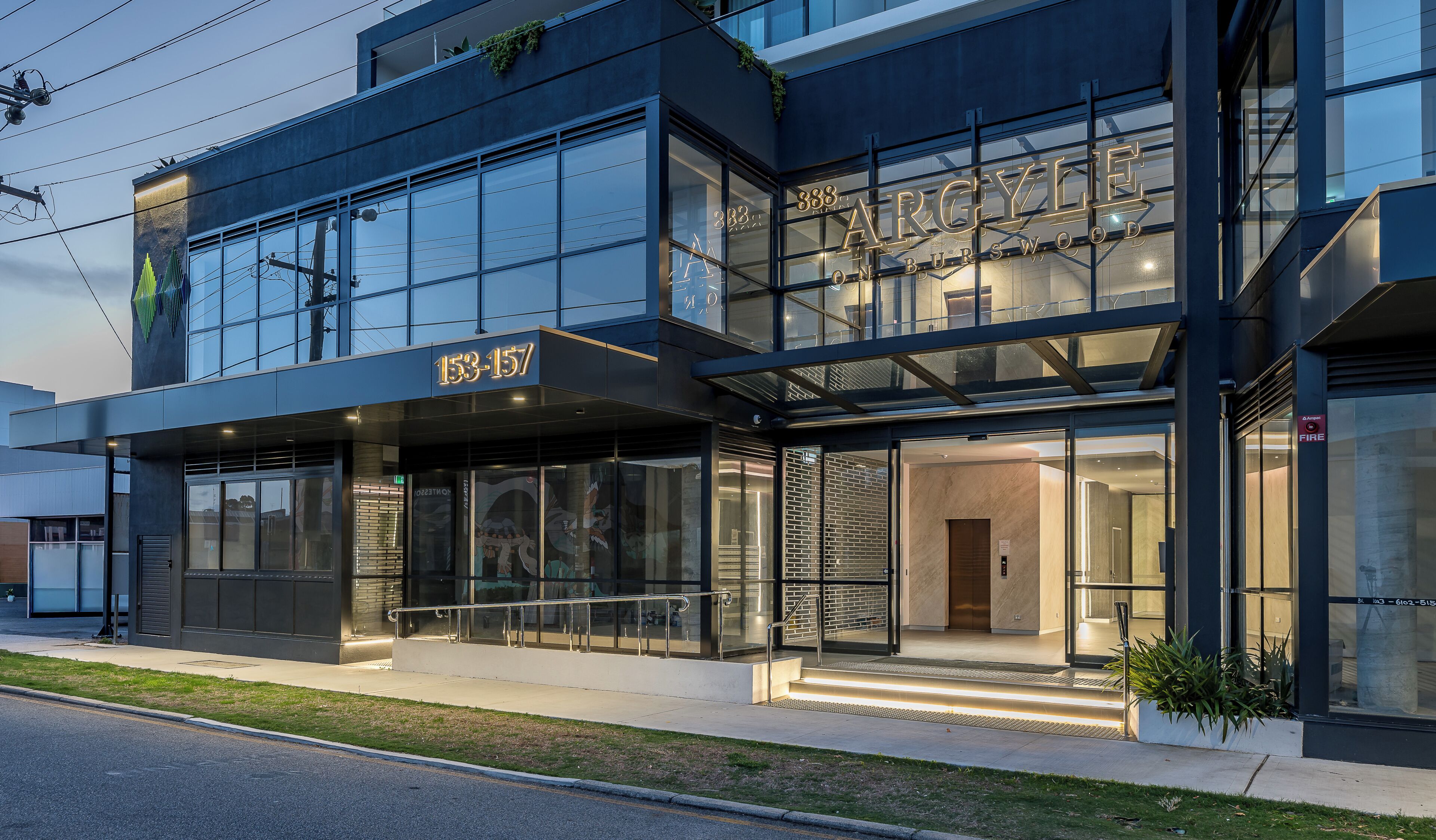 A modern building with a glass facade, a prominent address sign, and a fire safety sign.