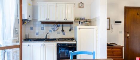 A kitchen with white cabinets, a stove, an oven, and a dining table with chairs.