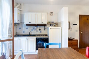Una cocina con armarios blancos, estufa, horno y una mesa de comedor con sillas.