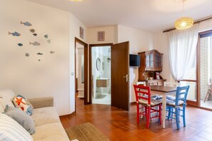 A living room with a sofa, a dining table with chairs, a kitchen area, and a bathroom visible through an open door. - A cozy 50 sqm apartment, ideal for up to 4 people, located on the first floor of a building with an elevator.The accommodation is located in Antignano, an elegant coastal and residential area of ​​Livorno, renowned for its tranquility and proximity t (Livorno)