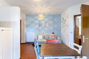 A dining area with a wooden table and chairs, a sofa with cushions, a radiator, and wall art. - A cozy 50 sqm apartment, ideal for up to 4 people, located on the first floor of a building with an elevator.The accommodation is located in Antignano, an elegant coastal and residential area of ​​Livorno, renowned for its tranquility and proximity t (Livorno)
