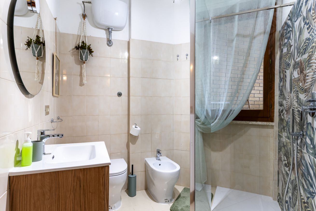 Un baño con inodoro, bidé, lavamanos, espejo y cortina de ducha.