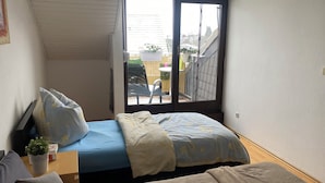 Ein kleines Schlafzimmer mit zwei Betten, einem Fenster und Blick ins Freie.