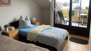 Ein Schlafzimmer mit Bett, Nachttischen, einem Fenster und Blick ins Freie.