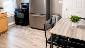 A modern kitchen with a stainless steel refrigerator, a stove, and a dining table with chairs. - 2-bedroom apartment in Lewiston near CMCC (Lewiston)