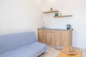 Una pequeña cocina americana con un lavamanos, una cafetera y un estante sobre la encimera.