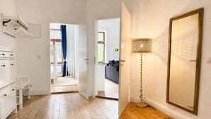 Un corridoio con pavimento in legno, un armadio bianco, uno specchio e una lampada.