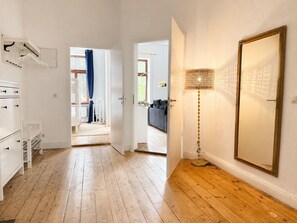 Ein Flur mit Holzdielen, einem weißen Kleiderschrank, einem Spiegel und einer Lampe.