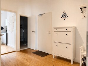 Ein Zimmer mit Holzboden, einem weißen Kleiderschrank mit zwei Schubladen, einer Tür und einer Wanddekoration.
