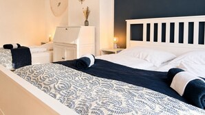 Una camera da letto con un letto, comodini, una cassettiera, una bussola appesa al muro e un vaso con fiori secchi.