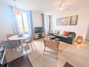 Ein modernes Wohnzimmer mit Essbereich, einer Couch, einem Fernseher und Kunstwerken an der Wand.