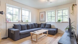 A modern living room with a grey sectional sofa, a wooden coffee table, and a TV stand. - Gamla Wallesvägen 10 - Bruksvallarna (Bruksvallarna)