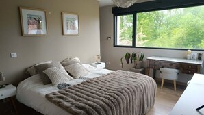 Una camera da letto con un letto, comodini, una scrivania e una finestra vista alberi.