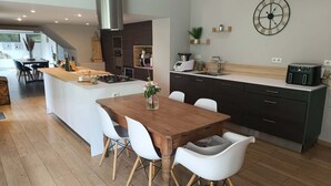 Una cucina moderna con isola centrale, sedie bianche e tavolo da pranzo.