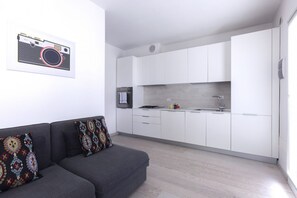 A modern kitchen with white cabinets, a built-in oven, and a grey sofa with patterned cushions. - GuestHost - Florence Modern & Quiet Nest (Firenze)